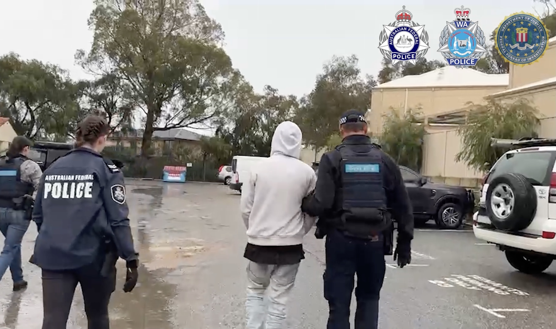 aussie-perp-walk-teampcp a photo of australian police walking with one of the alleged TeamPCP hackers in handcuffs