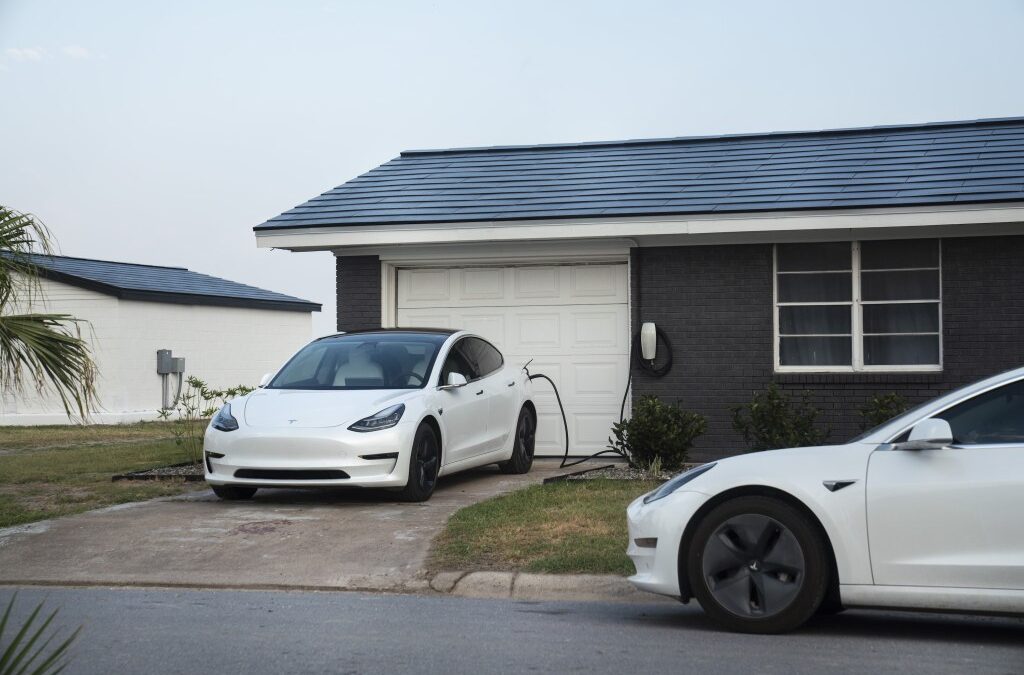 Tesla vehicles parked outside a home with a Tesla Solar Roof.