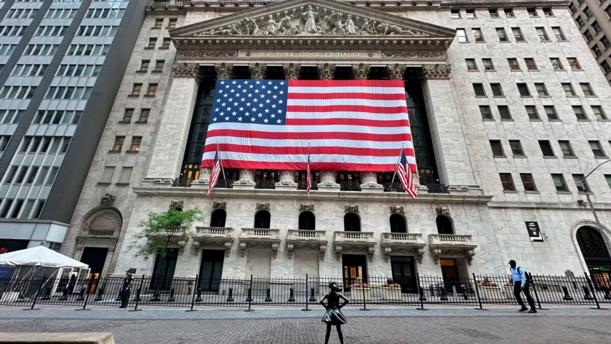 People pass the New York Stock Exchange on the street.