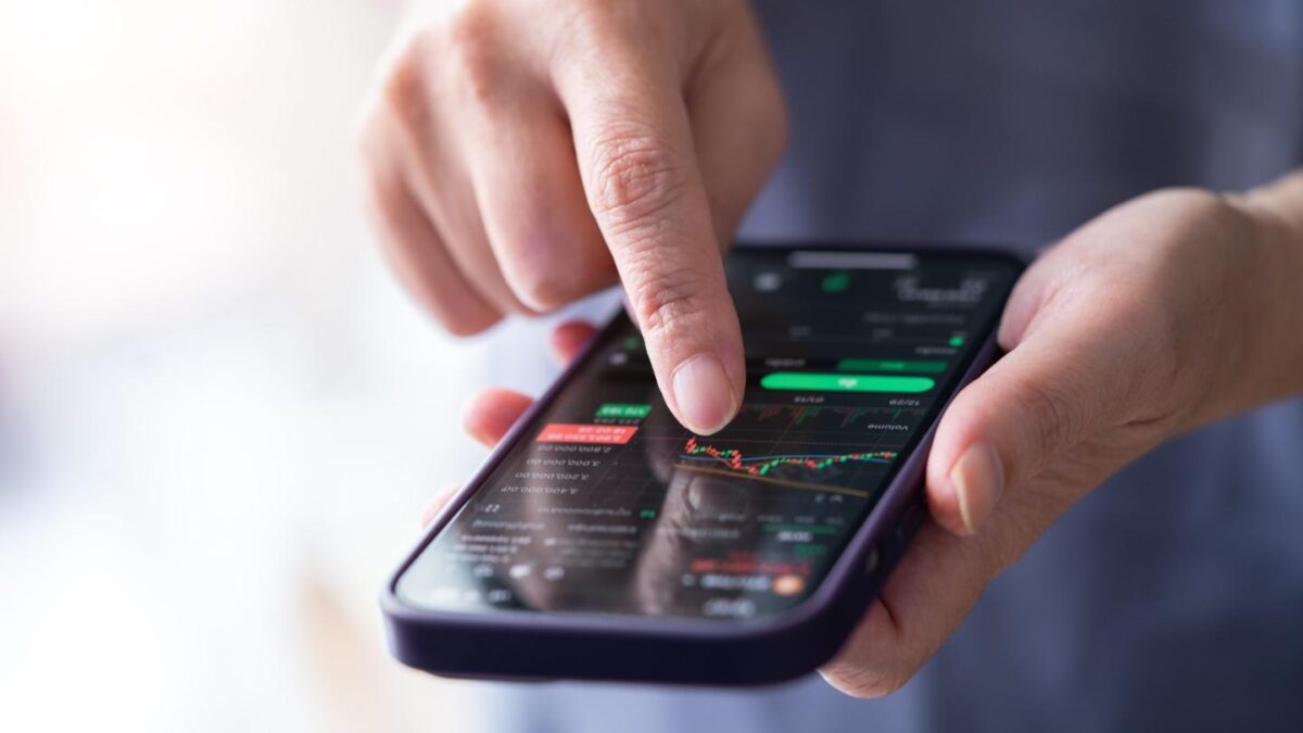 Person using index finger on phone to check trading activity.
