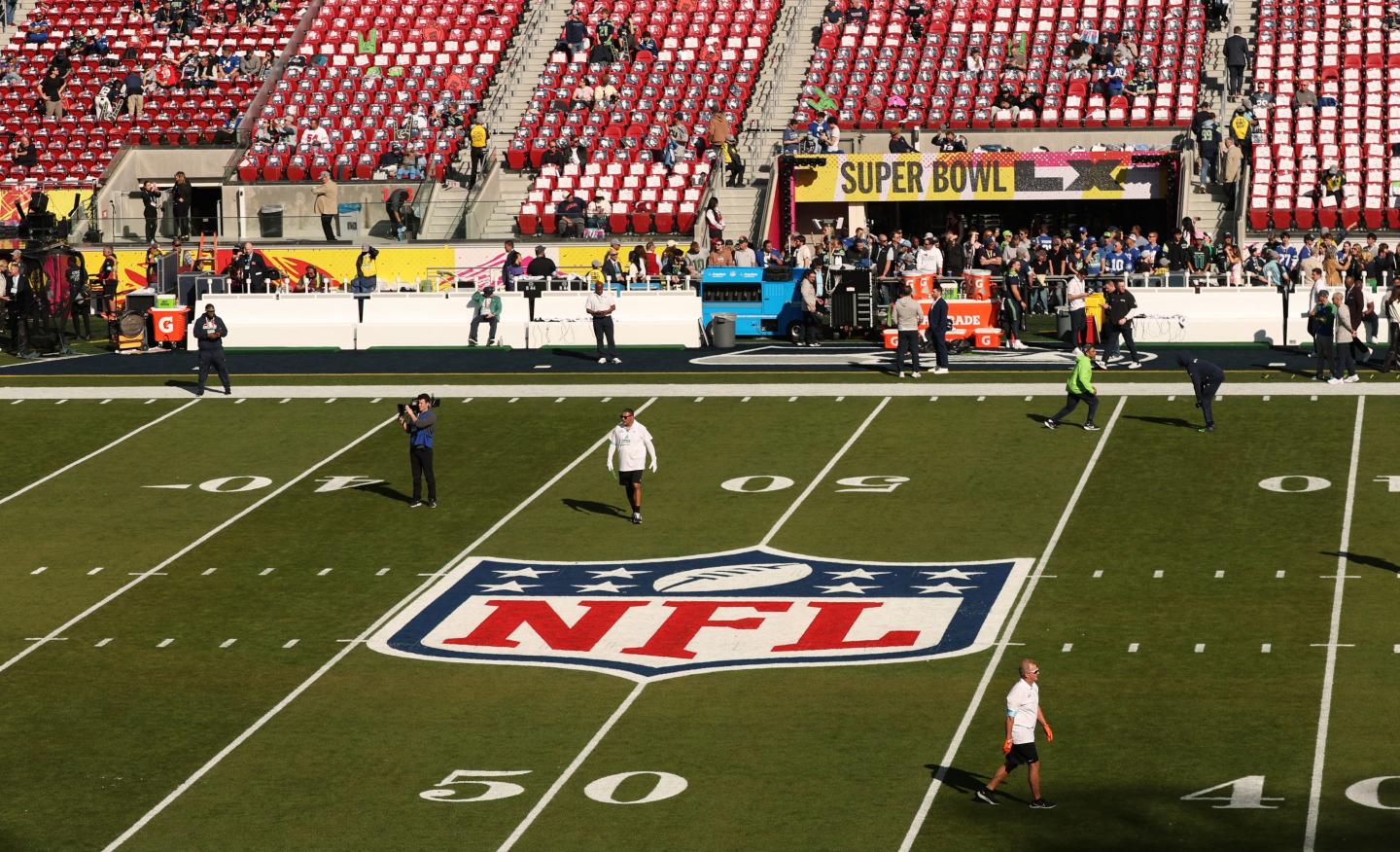 NFL football field with personnel walking it before the Super Bowl final