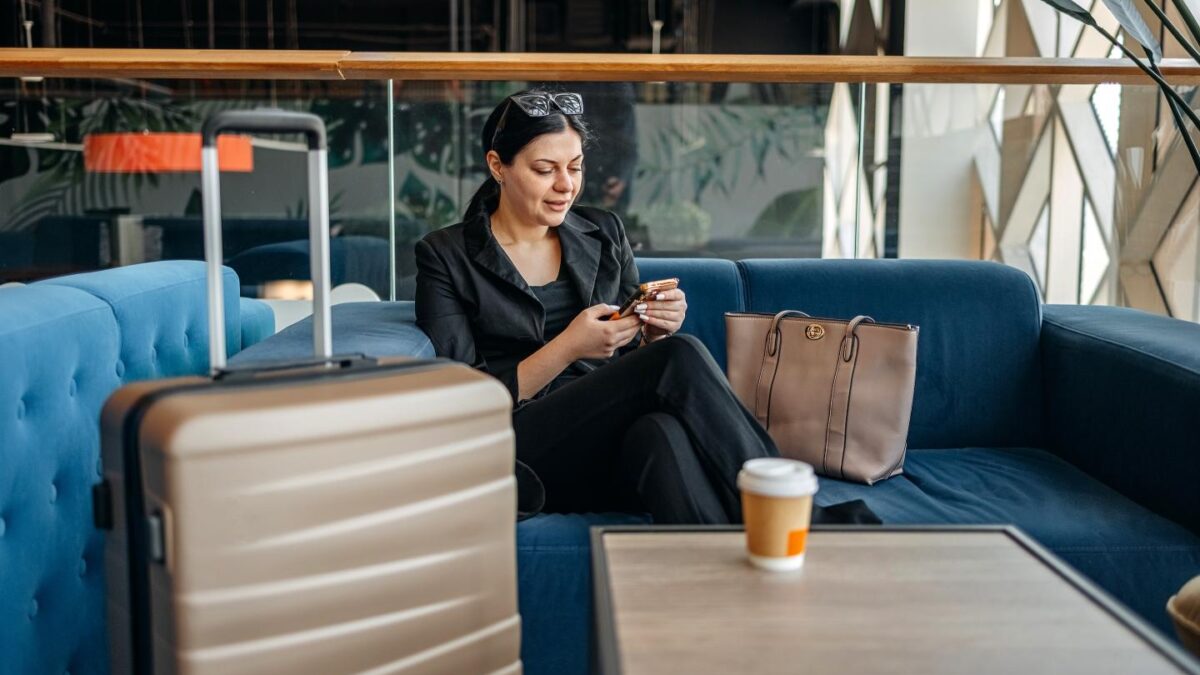 Young woman with suitcase close to her in an airport lounge